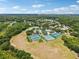 An aerial view of tennis courts and fields in a community with homes, trees, and a lake under a partly cloudy sky at 16910 Equestrian Trl, Odessa, FL 33556
