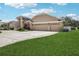Spacious home featuring a manicured lawn, concrete driveway, and a tan stucco exterior with a three-car garage at 16910 Equestrian Trl, Odessa, FL 33556