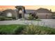 Inviting two-story tan home featuring an arched entryway, a three-car garage, and beautifully landscaped grounds at 16910 Equestrian Trl, Odessa, FL 33556