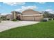 Spacious home featuring a manicured lawn, concrete driveway, and a tan stucco exterior with a three-car garage at 16910 Equestrian Trl, Odessa, FL 33556