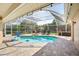 Sparkling screened-in pool with stone patio, lounge chairs, and lush landscaping at 16910 Equestrian Trl, Odessa, FL 33556