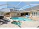 Inviting pool and spa with a screened-in enclosure, surrounded by a stone patio at 16910 Equestrian Trl, Odessa, FL 33556
