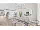 Stylish dining area with a modern chandelier, glass table, and open view to the kitchen and living spaces at 17206 Luminous Ave, Venice, FL 34293