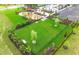 Aerial view of a fenced dog park in a new community with trees and grass, playground in background at 17206 Luminous Ave, Venice, FL 34293