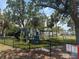 Outdoor playground with playground equipment, green grass, palm trees, and a black chain link fence at 1735 Maryland Ne Ave, St Petersburg, FL 33703