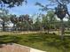 Green playground with swings and playground equipment surrounded by palm trees and a black chain link fence at 1735 Maryland Ne Ave, St Petersburg, FL 33703