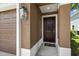 Close-up of a brown front door framed by stucco walls and a decorative lantern at 2131 River Turia Cir, Riverview, FL 33578