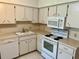 The kitchen features white cabinets, standard appliances, laminate countertop, and a sink under the window at 2287 Philippine Dr # 29, Clearwater, FL 33763