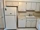 The kitchen features white cabinets, standard appliances, laminate countertop, and a sink under the window at 2287 Philippine Dr # 29, Clearwater, FL 33763