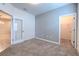 A neutral carpeted bedroom features gray walls, a walk-in closet, and access to another room at 32829 Woodthrush Way, Wesley Chapel, FL 33545