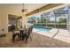 Covered outdoor patio with dining set overlooking the sparkling swimming pool and green landscape at 5429 Legend Hills Ln, Spring Hill, FL 34609