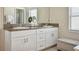 Bathroom featuring double granite vanity with white cabinets, vanity mirrors, and storage bench at 5457 Leslie Canyon Dr, Wimauma, FL 33598