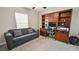 Cozy bedroom with a workspace featuring a bookshelf and a comfortable gray sofa at 5457 Leslie Canyon Dr, Wimauma, FL 33598