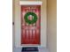 Inviting red front door adorned with a green wreath and 'Welcome' doormat at 5457 Leslie Canyon Dr, Wimauma, FL 33598