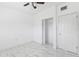 Clean bedroom featuring updated ceiling fan, closet, and sleek tile flooring at 6010 Blossom Ave, Tampa, FL 33614