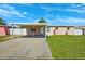 A quaint single-story home featuring a carport, manicured lawn, and freshly painted exterior under a bright blue sky at 6010 Blossom Ave, Tampa, FL 33614