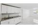 Bright kitchen featuring white cabinets, granite countertops, and modern flooring at 6010 Blossom Ave, Tampa, FL 33614