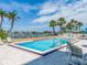 Community pool with lounge chairs, tables, and lush palm trees for a resort-like feel by the intercoastal waterway at 690 Island Way # 1011, Clearwater Beach, FL 33767