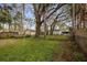 Spacious backyard with mature trees, partial fencing, and a glimpse of neighboring homes at 7247 Oelsner St, New Port Richey, FL 34652