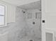 This bathroom features elegant marble tiling in the walk-in shower with dual shower heads and stylish shower caddy at 9155 125Th St, Seminole, FL 33772