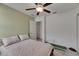 Neutral bedroom with a ceiling fan, ensuite door, and a personal treadmill for in-home fitness at 9907 Spanish Lime Ct, Riverview, FL 33578
