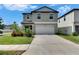Charming two-story home with a well-manicured lawn, colorful landscaping, and a two-car garage on a sunny day at 9907 Spanish Lime Ct, Riverview, FL 33578