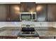 Close up of stainless steel appliances including a microwave and range, with granite countertops and dark cabinets at 9907 Spanish Lime Ct, Riverview, FL 33578