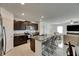 Open kitchen with an island featuring barstool seating, granite countertops, stainless appliances, and dark cabinetry at 9907 Spanish Lime Ct, Riverview, FL 33578
