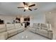 Open-concept living room view to the kitchen with neutral tones, tile floors, and a ceiling fan at 9907 Spanish Lime Ct, Riverview, FL 33578