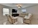 Sunlit living room with reclining sofas, a modern entertainment center, and tile floors at 9907 Spanish Lime Ct, Riverview, FL 33578