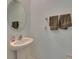 Stylish powder room with a pedestal sink, round mirror, and neutral-toned towels at 9907 Spanish Lime Ct, Riverview, FL 33578
