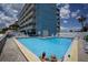 Outdoor pool area with lounge chairs, a Tiki bar, and views of the building's exterior at 9980 Gulf Blvd # 603, Treasure Island, FL 33706