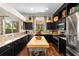 Well-equipped kitchen featuring sleek black cabinets, granite countertops, a butcher block island, and modern appliances at 1133 Split Silk St, Valrico, FL 33594