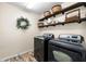 Functional laundry room with modern appliances, decorative shelves, and stylish tile flooring at 1133 Split Silk St, Valrico, FL 33594
