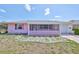 Charming single-story home with a pink exterior, decorative lattice porch, and simple rock garden at 1207 Norwich Cir, Sun City Center, FL 33573