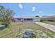 Charming pink exterior with rock garden, address stone, a driveway, and a screened front porch at 1207 Norwich Cir, Sun City Center, FL 33573