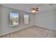 Empty bedroom with neutral walls, carpet, ceiling fan, and two windows overlooking a neighborhood at 12150 Ledbury Commons Dr, Gibsonton, FL 33534