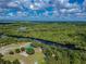 Scenic aerial view of property with lush greenery and tranquil waterways under blue skies with fluffy clouds at 1616 Lightfoot Rd, Wimauma, FL 33598