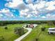 Aerial shot of a well-kept farm featuring expansive green pastures, farm buildings, and a tree-lined drive at 1616 Lightfoot Rd, Wimauma, FL 33598