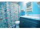 Bright bathroom featuring a vanity with white sink and blue cabinets, plus shower with fun fish curtain at 1616 Lightfoot Rd, Wimauma, FL 33598