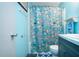 Bright bathroom featuring a vanity with white sink and blue cabinets, plus shower with fun fish curtain at 1616 Lightfoot Rd, Wimauma, FL 33598