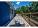 Outdoor deck featuring wood railing, side view of house, and surrounded by large trees at 1616 Lightfoot Rd, Wimauma, FL 33598