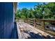 Outdoor deck featuring a wood railing, side view of house, and surrounded by large trees at 1616 Lightfoot Rd, Wimauma, FL 33598