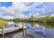 Waterfront dock featuring a wooden walkway under sunny skies with reflection in water at 1616 Lightfoot Rd, Wimauma, FL 33598