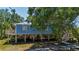 Elevated stilt home with wooden supports and staircase, set amidst a lush, green landscape at 1616 Lightfoot Rd, Wimauma, FL 33598