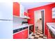 Modern kitchen features bright red cabinets, sleek appliances, and checkerboard flooring at 1616 Lightfoot Rd, Wimauma, FL 33598