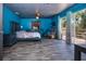 Spacious main bedroom featuring blue walls, wood floors, ceiling fan, and sliding glass door to the outside deck at 1616 Lightfoot Rd, Wimauma, FL 33598