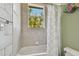 Bathroom featuring a tub with a shower curtain, toilet, and tiled walls with a view of the window at 2605 59Th S St, Gulfport, FL 33707