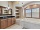 This bathroom features a soaking tub, and a wooden vanity with black countertop and shelves for storage at 2605 59Th S St, Gulfport, FL 33707