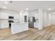 Modern kitchen with white cabinets, stainless steel appliances, and a center island overlooking wood grain flooring at 2651 Burri Ter, North Port, FL 34288